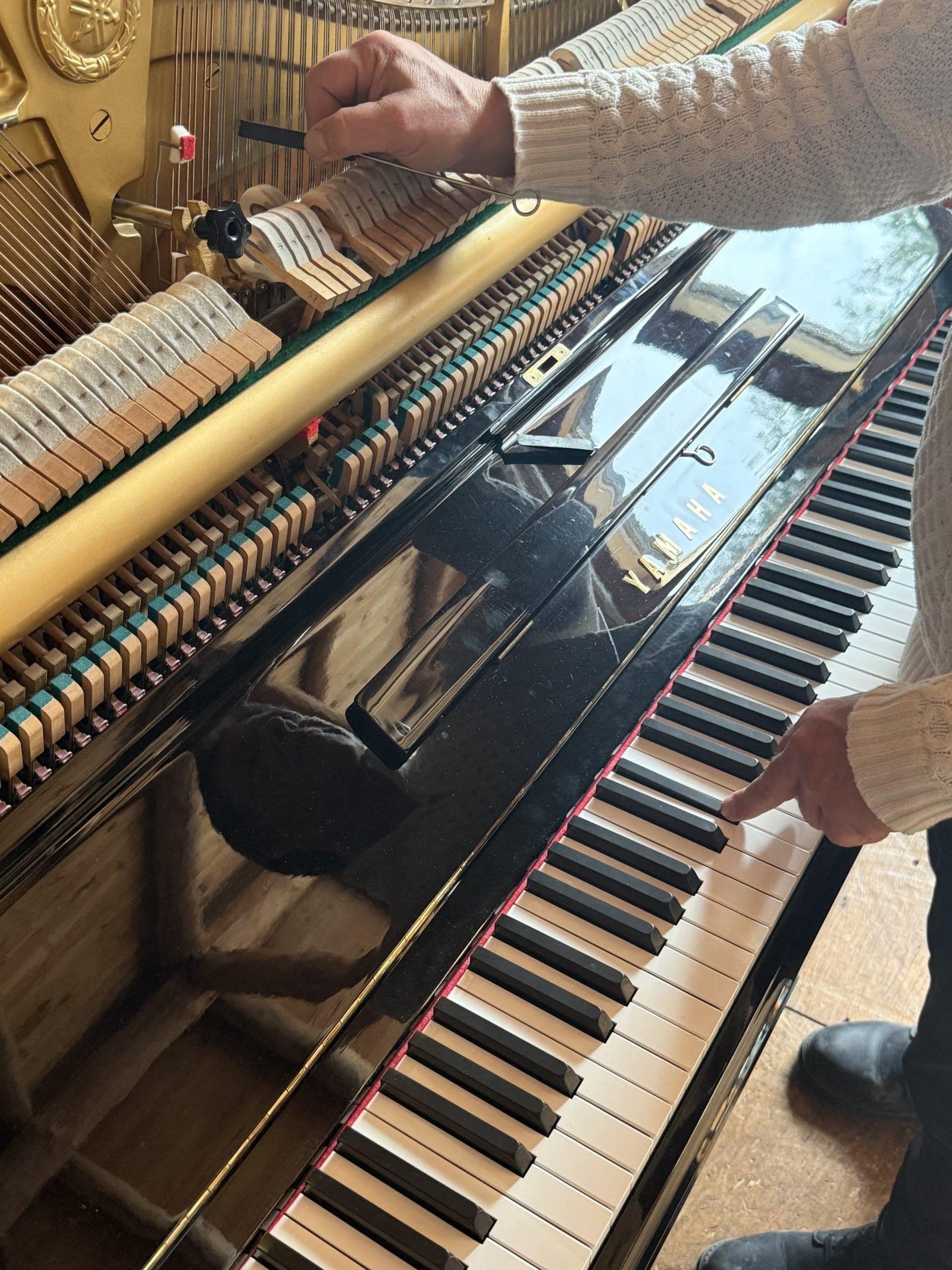 Piano tuner in action, view of hands on tuning pins